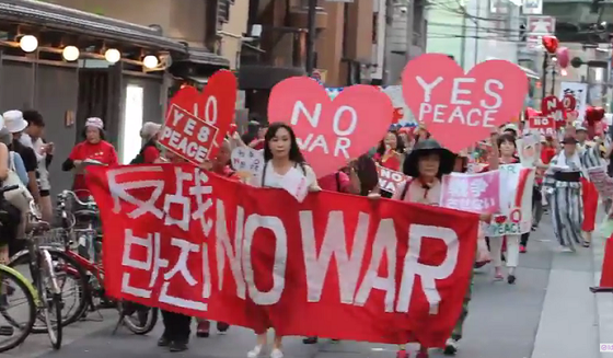 2015年7月19日に大阪市内で行われた「戦争反対！　愛と平和の女子パレ」の様子。支那語（簡体字）と朝鮮語（ハングル）と英語の横断幕